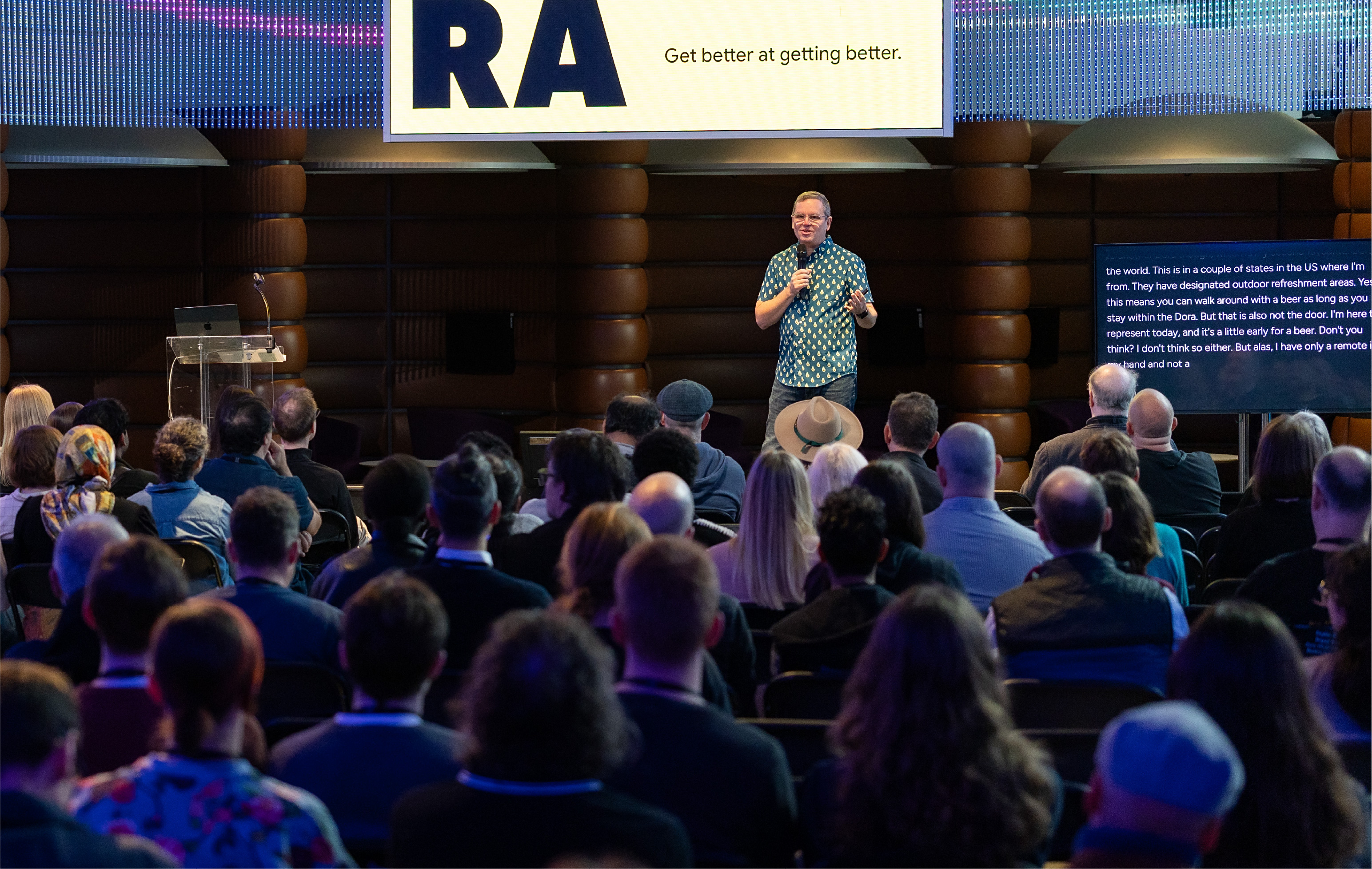 Professional conference with live captioning by Procast.ai - speaker presenting to audience with captions displayed on screen, supporting hearing impaired attendees